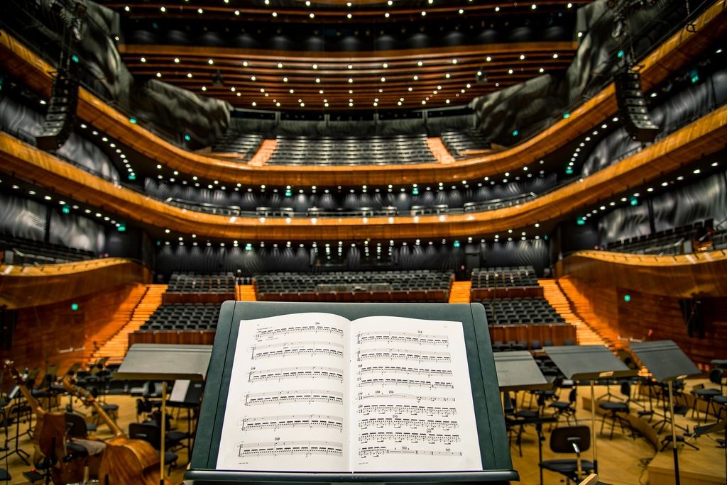 An open musical score on a conductor’s stand in a concert hall